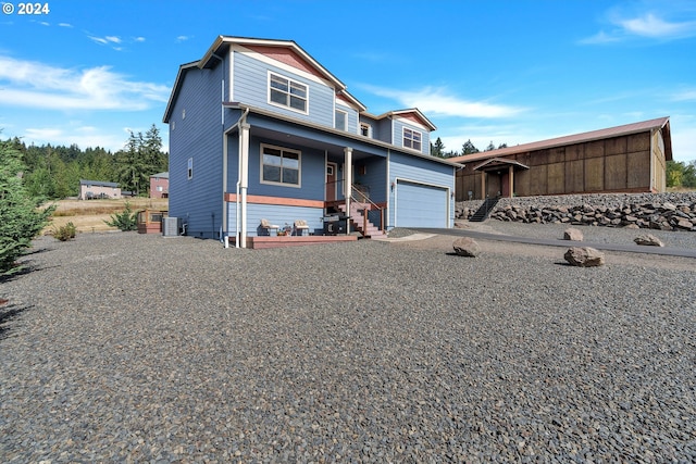 view of front of house with central air condition unit, a porch, and a garage