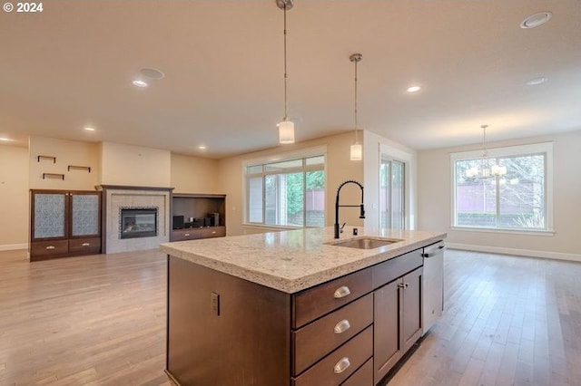 kitchen featuring sink, light hardwood / wood-style flooring, a notable chandelier, an island with sink, and pendant lighting