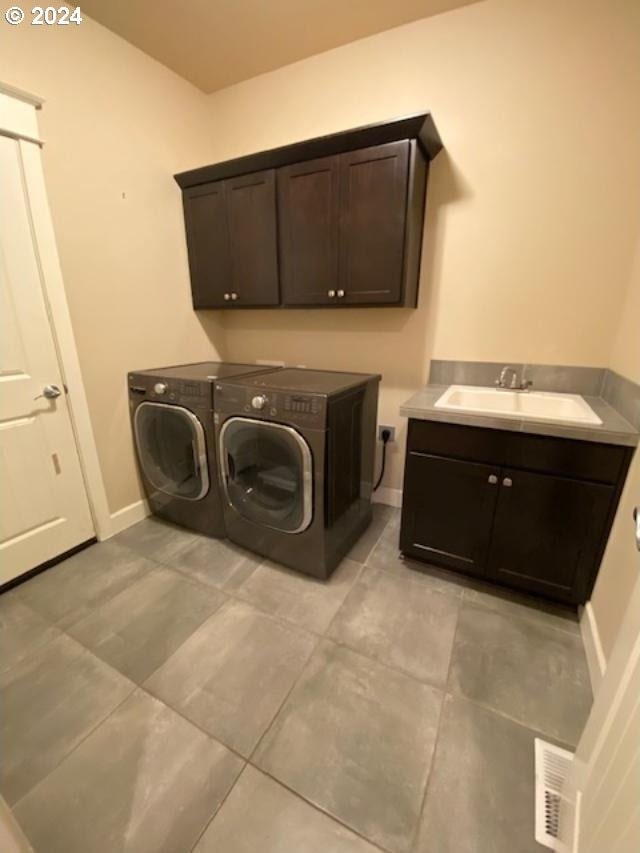 laundry area with cabinets, separate washer and dryer, sink, and light tile patterned floors