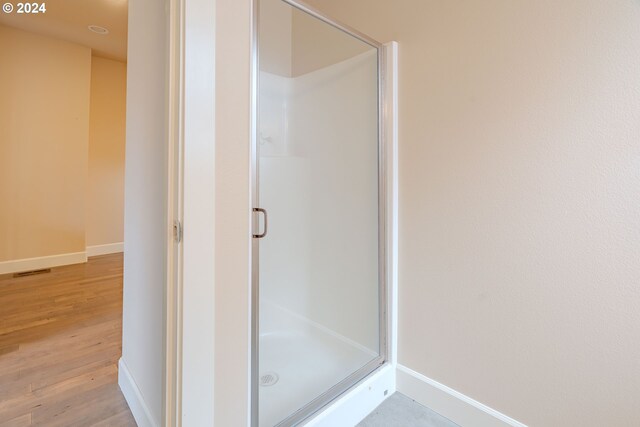 bathroom featuring a shower with shower door and hardwood / wood-style flooring