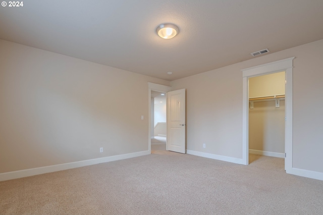 unfurnished bedroom with light carpet, a spacious closet, and a closet