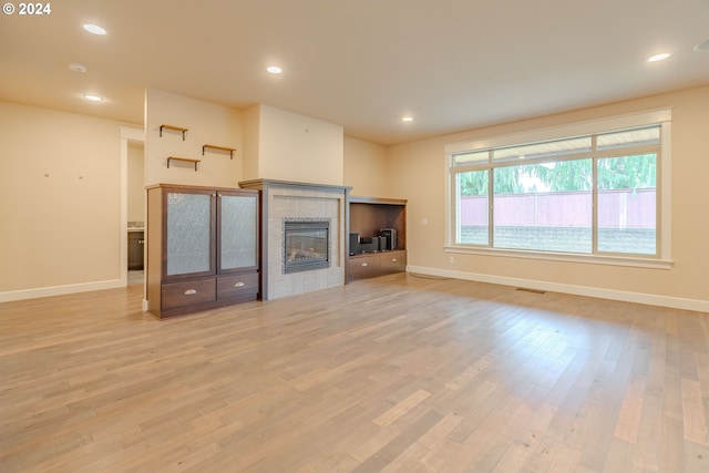 unfurnished living room with light wood-type flooring and a brick fireplace