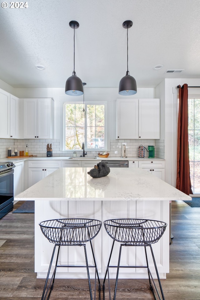 kitchen with a kitchen island, pendant lighting, dark wood-type flooring, and white cabinetry