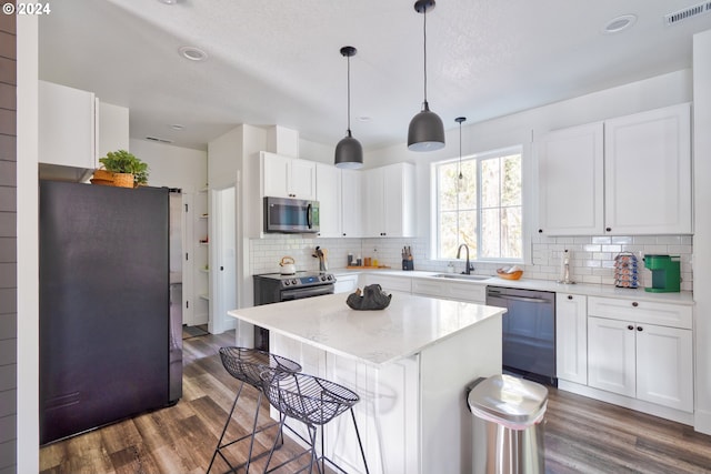 kitchen featuring dark hardwood / wood-style flooring, white cabinetry, backsplash, stainless steel appliances, and sink