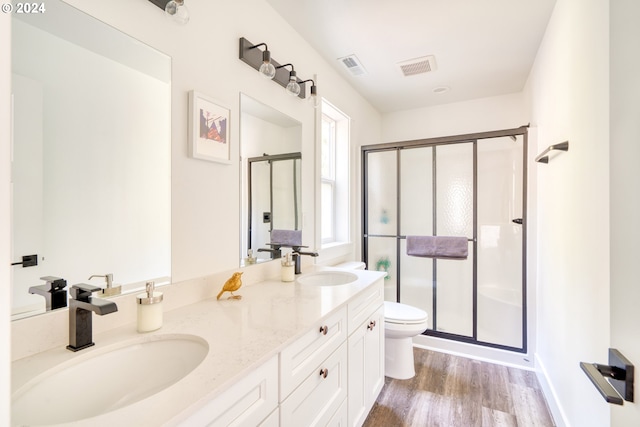 bathroom featuring dual bowl vanity, an enclosed shower, toilet, and hardwood / wood-style floors