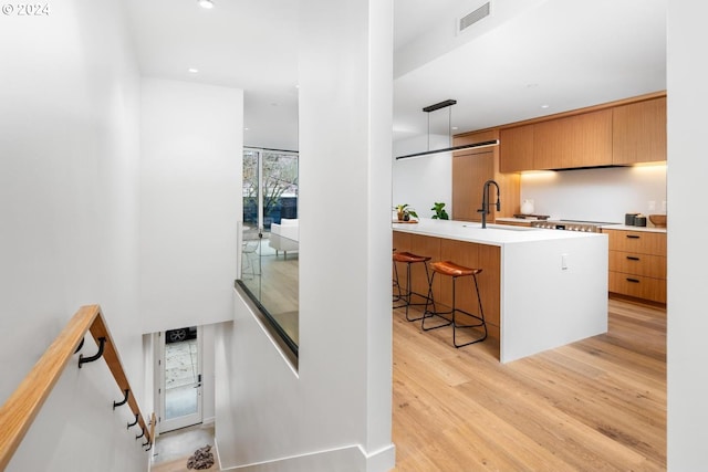 kitchen with pendant lighting, a kitchen breakfast bar, sink, light wood-type flooring, and kitchen peninsula