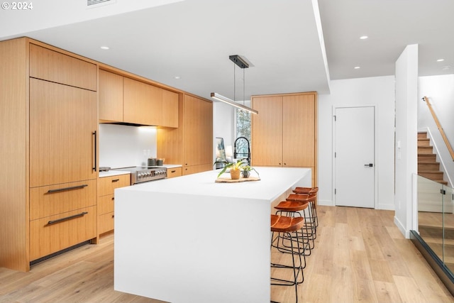 kitchen with pendant lighting, a center island, light brown cabinetry, and light hardwood / wood-style flooring