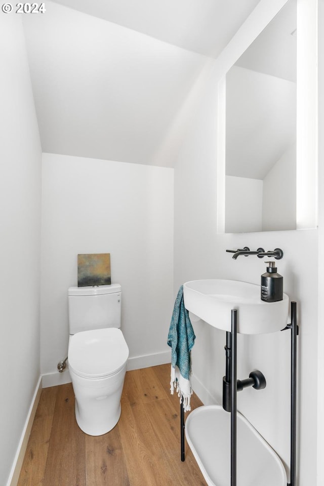 bathroom featuring hardwood / wood-style floors, vaulted ceiling, and toilet