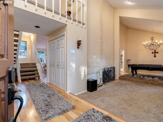 entrance foyer featuring lofted ceiling, pool table, hardwood / wood-style flooring, a notable chandelier, and a textured ceiling