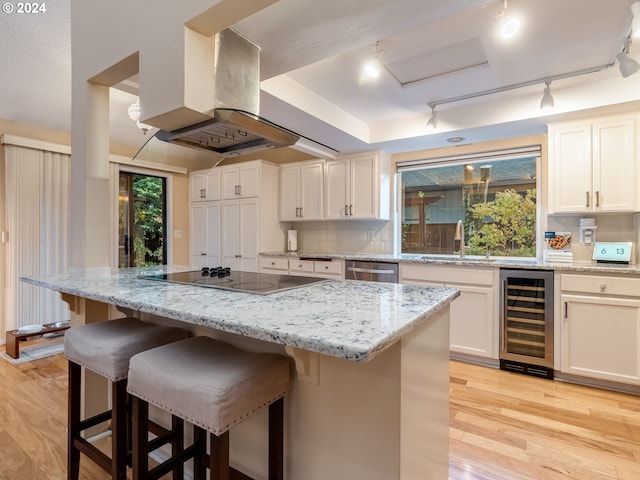 kitchen featuring island exhaust hood, wine cooler, a center island, and rail lighting