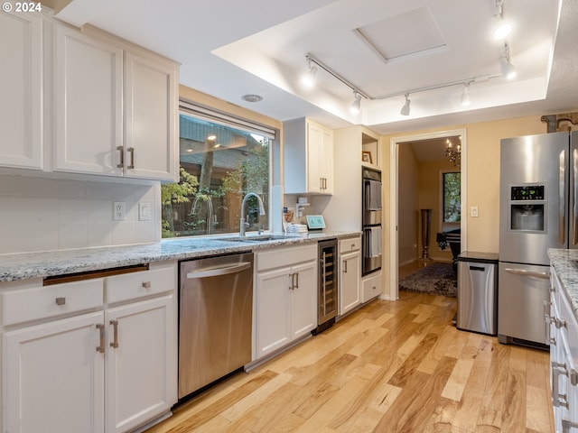 kitchen with white cabinets, wine cooler, sink, light hardwood / wood-style floors, and stainless steel appliances