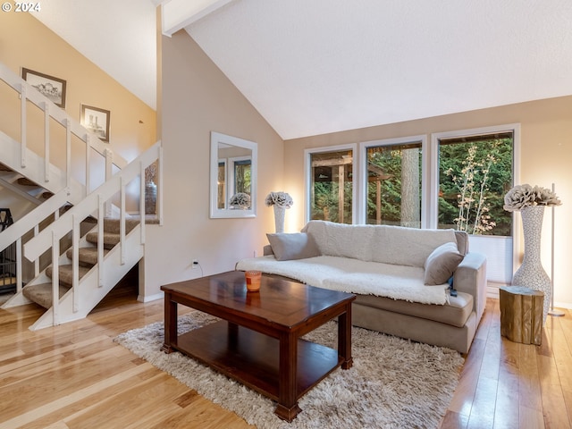 living room with beamed ceiling, light hardwood / wood-style flooring, and high vaulted ceiling