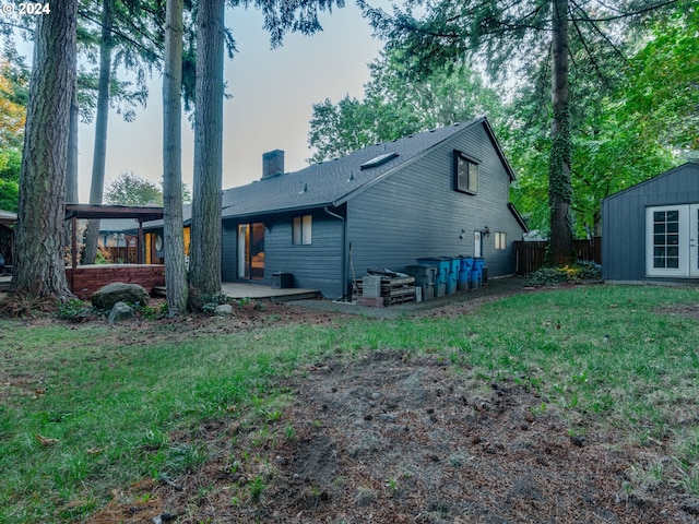 rear view of property with a patio, a shed, and a lawn