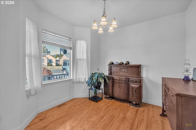 miscellaneous room with an inviting chandelier and light wood-type flooring