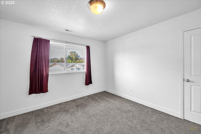 empty room with a textured ceiling and carpet floors