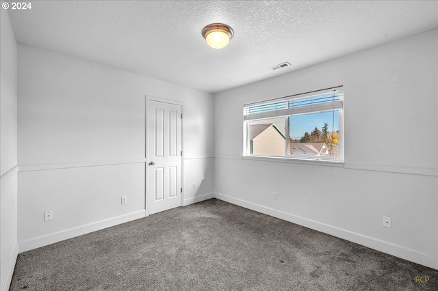 carpeted empty room with a textured ceiling