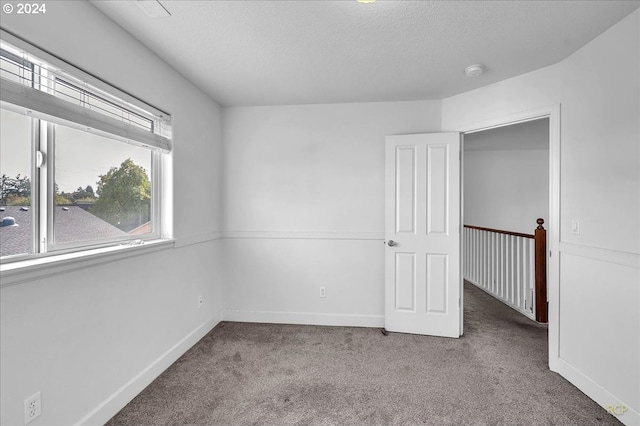 spare room featuring a textured ceiling and carpet flooring