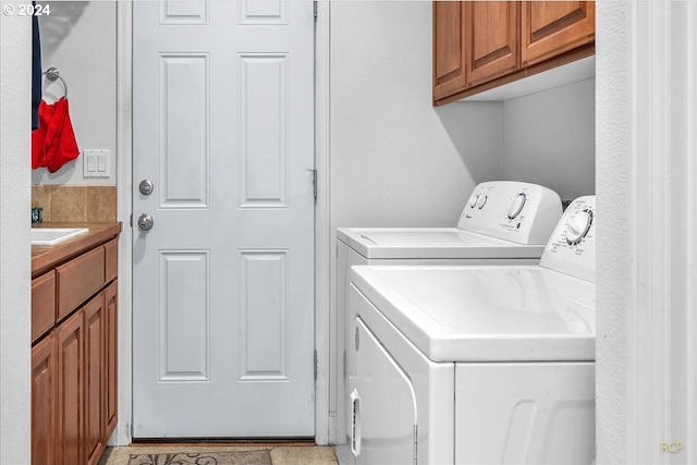 clothes washing area with sink, cabinets, and separate washer and dryer