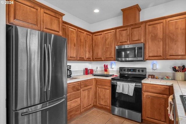 kitchen featuring tile countertops, light tile patterned flooring, and stainless steel appliances