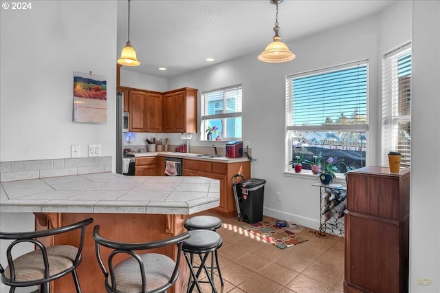 kitchen with kitchen peninsula, a breakfast bar area, appliances with stainless steel finishes, pendant lighting, and sink