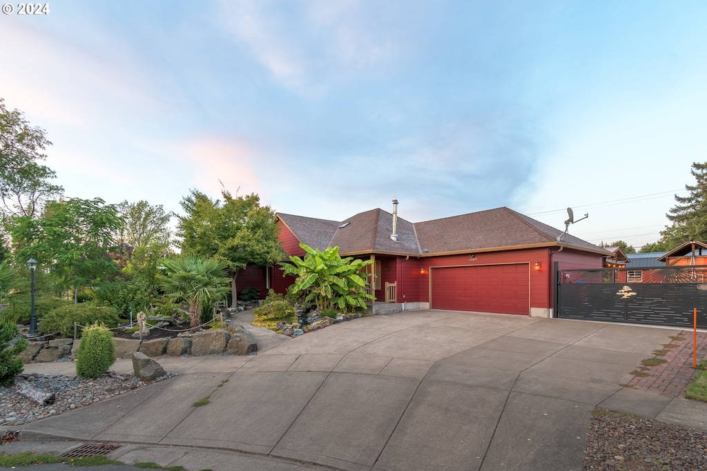 view of front of house with a gate, a garage, driveway, and fence