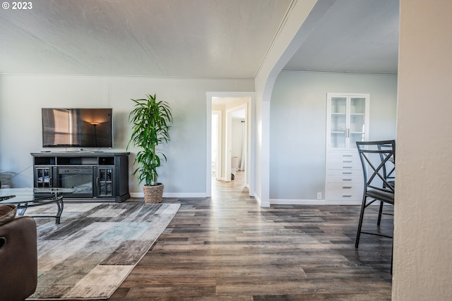 living room with crown molding and dark wood-type flooring