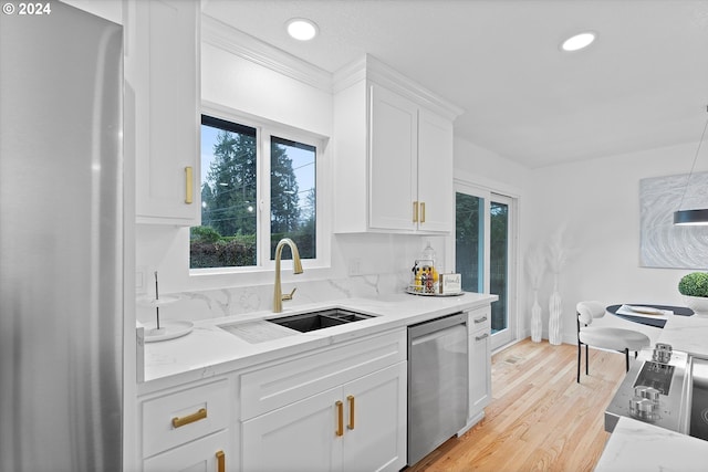 kitchen with sink, light hardwood / wood-style flooring, light stone counters, white cabinetry, and stainless steel appliances