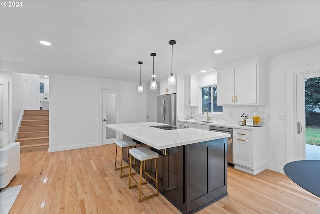 kitchen with plenty of natural light, a kitchen island, white cabinetry, and stainless steel appliances