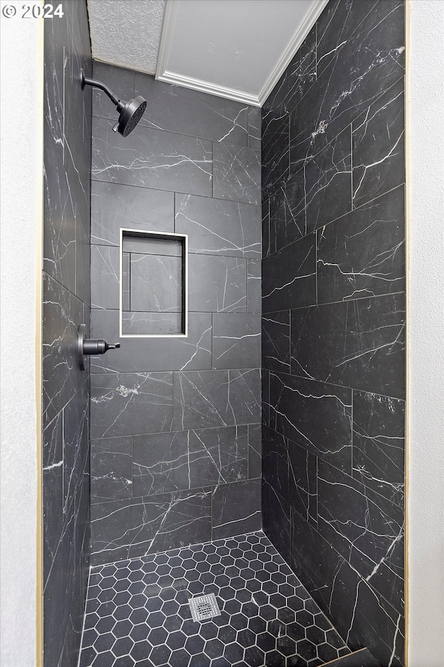 bathroom with tiled shower and ornamental molding