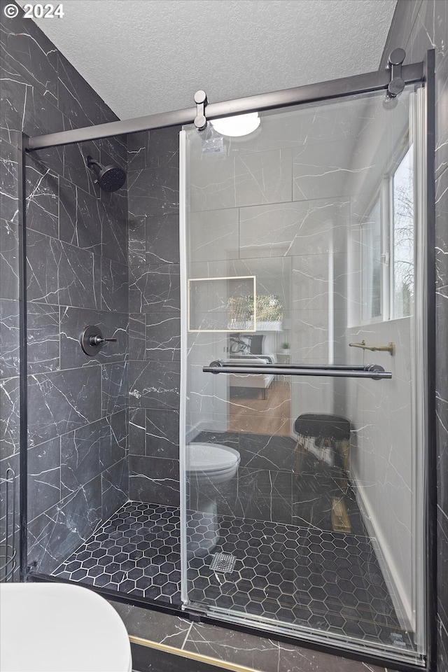 bathroom with toilet, an enclosed shower, and a textured ceiling