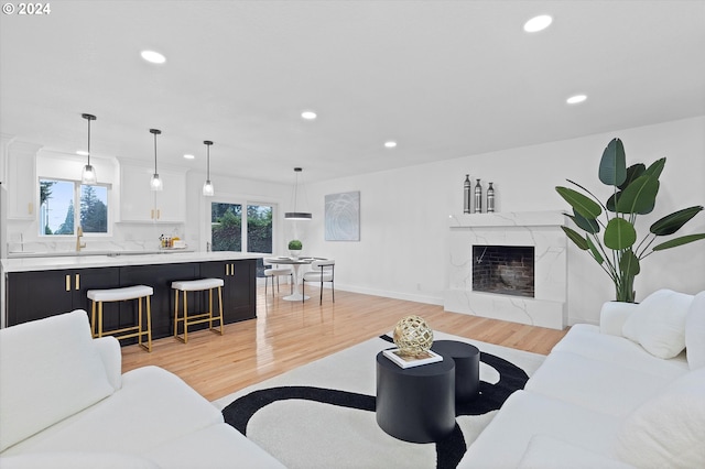 living room with light wood-type flooring, sink, and a premium fireplace