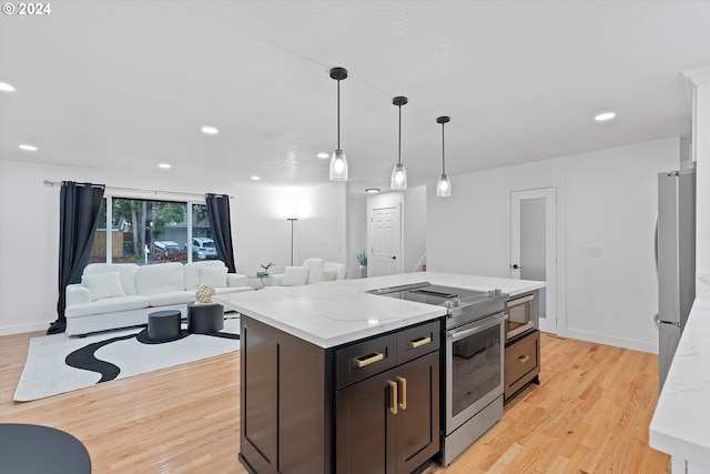 kitchen featuring light stone countertops, a center island, pendant lighting, light hardwood / wood-style floors, and appliances with stainless steel finishes