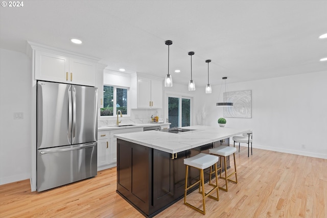 kitchen with stainless steel appliances, sink, white cabinetry, light hardwood / wood-style flooring, and a kitchen island