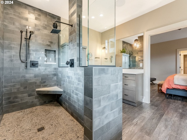 bathroom with tiled shower, wood-type flooring, and vanity