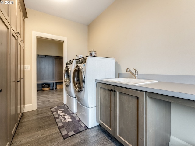 clothes washing area featuring cabinets, dark hardwood / wood-style flooring, sink, and washing machine and clothes dryer