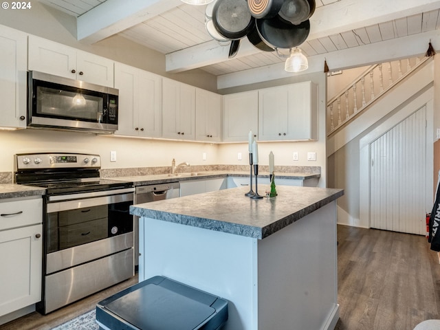 kitchen featuring beamed ceiling, stainless steel appliances, white cabinetry, and dark wood-type flooring