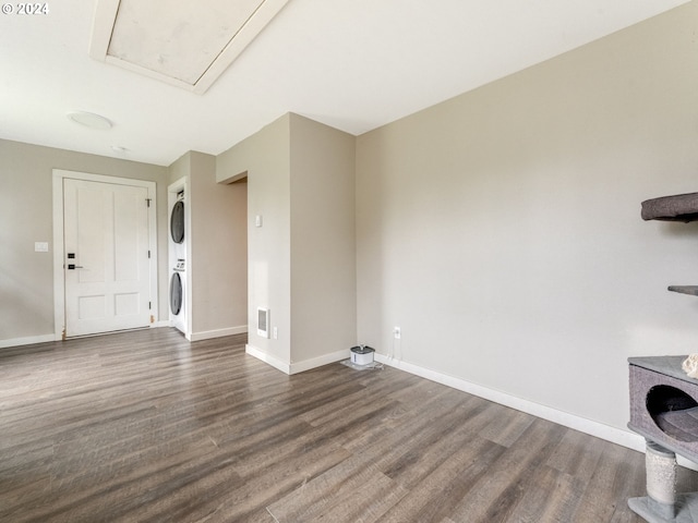 laundry area with dark wood-type flooring and stacked washer and clothes dryer