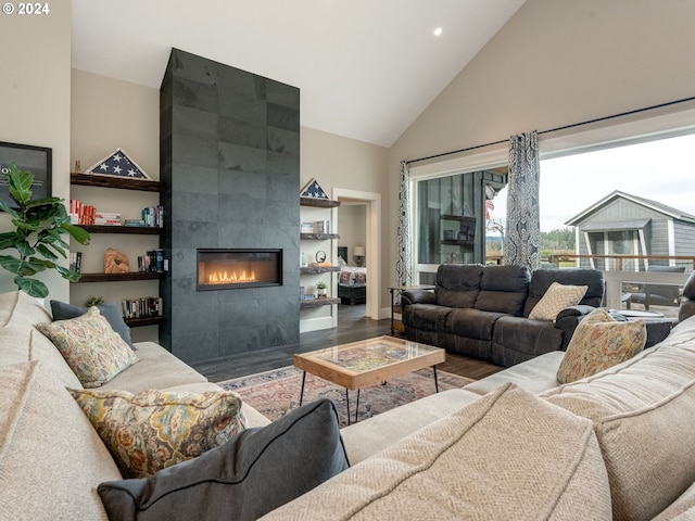 living room featuring wood-type flooring, high vaulted ceiling, and a tiled fireplace