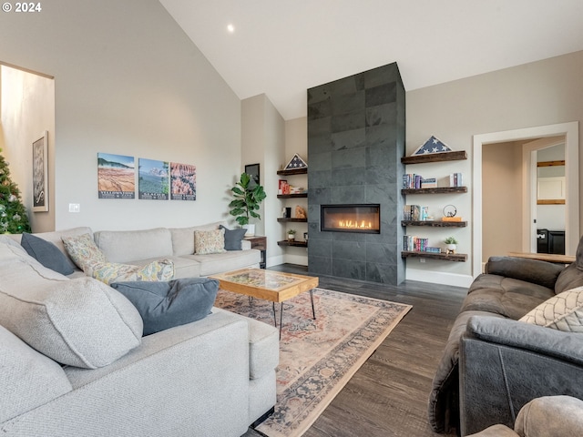 living room with dark hardwood / wood-style flooring, high vaulted ceiling, and a tiled fireplace