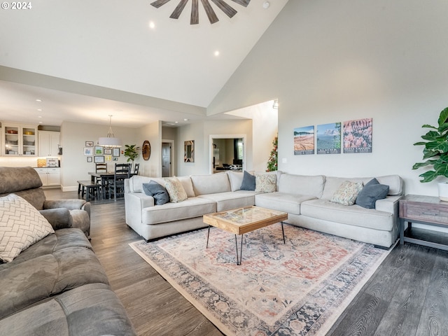 living room with ceiling fan, dark wood-type flooring, and high vaulted ceiling