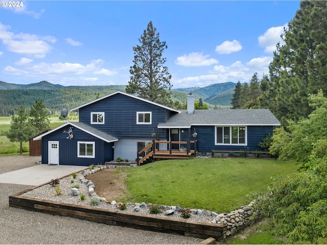 view of front facade with a front yard, a garage, and a deck with mountain view