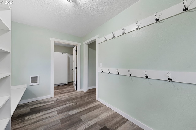 mudroom featuring heating unit, dark hardwood / wood-style floors, and a textured ceiling