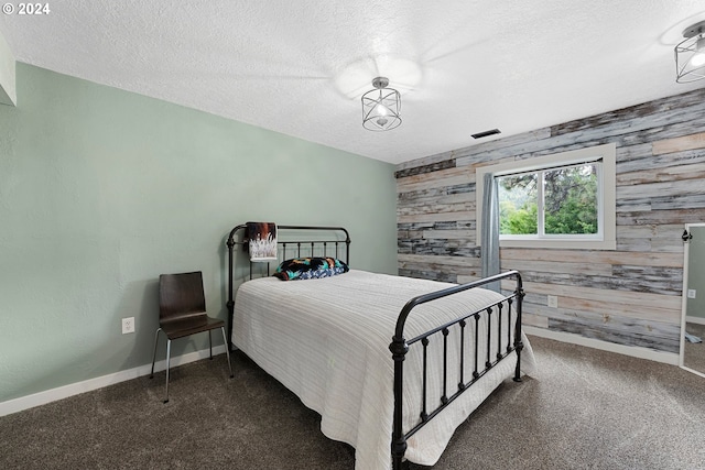 carpeted bedroom featuring a textured ceiling and wooden walls