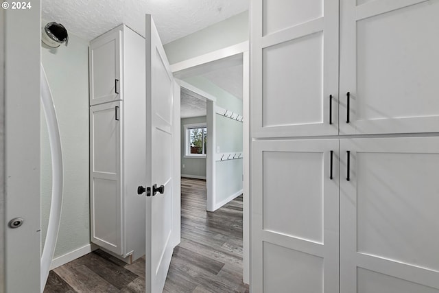 corridor with hardwood / wood-style floors and a textured ceiling