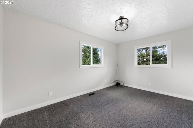 carpeted empty room with a textured ceiling