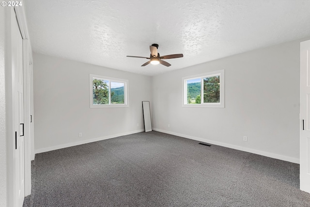 carpeted empty room with ceiling fan and a textured ceiling