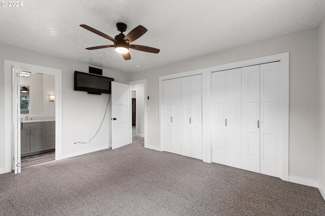 unfurnished bedroom with ensuite bath, ceiling fan, sink, carpet floors, and two closets