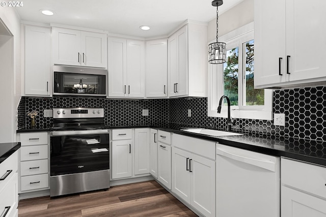 kitchen with sink, dark hardwood / wood-style floors, appliances with stainless steel finishes, decorative light fixtures, and white cabinetry