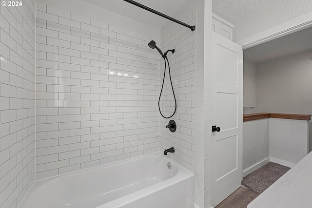 bathroom with hardwood / wood-style flooring, tiled shower / bath combo, and a textured ceiling