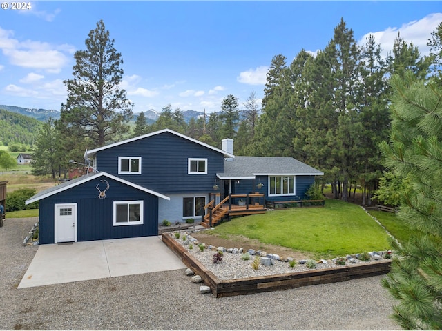 tri-level home featuring a deck with mountain view, a patio, and a front yard